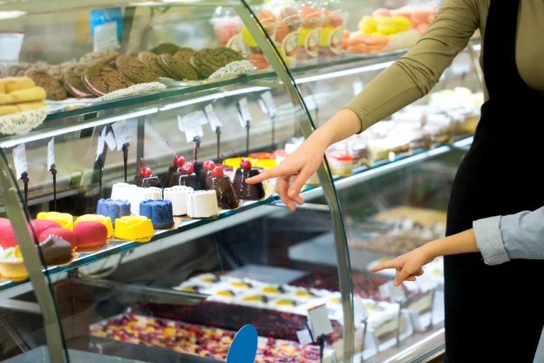 A young family with a child chooses dessert in the window of Cake Display Fridge