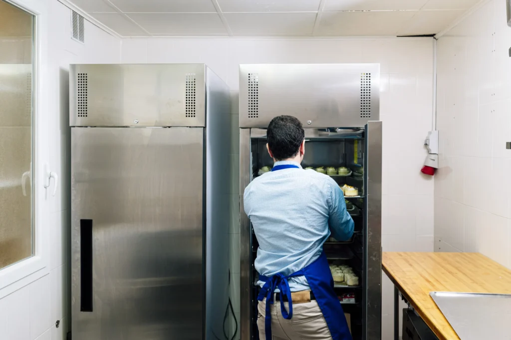 man-storing-handmade-cheesecakes-in-the-commercial-fridge-freezer