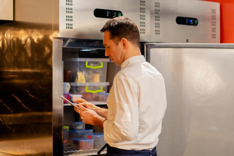 professional-kitchen-chef-looks-into-the-commercial-fridge freezer