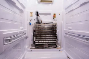 Refrigerator repair. Removing the rear panel of the freezer compartment. Evaporator coil with freezer thermostat
