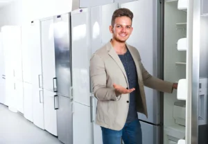 Young man purchasing new refrigerator in domestic appliances store